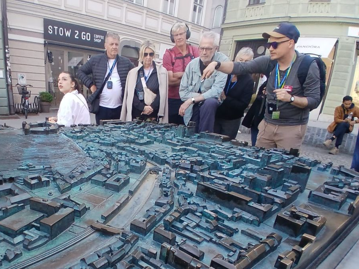 Guiding a group at the bronze model of Ljubljana, Prešernov trg